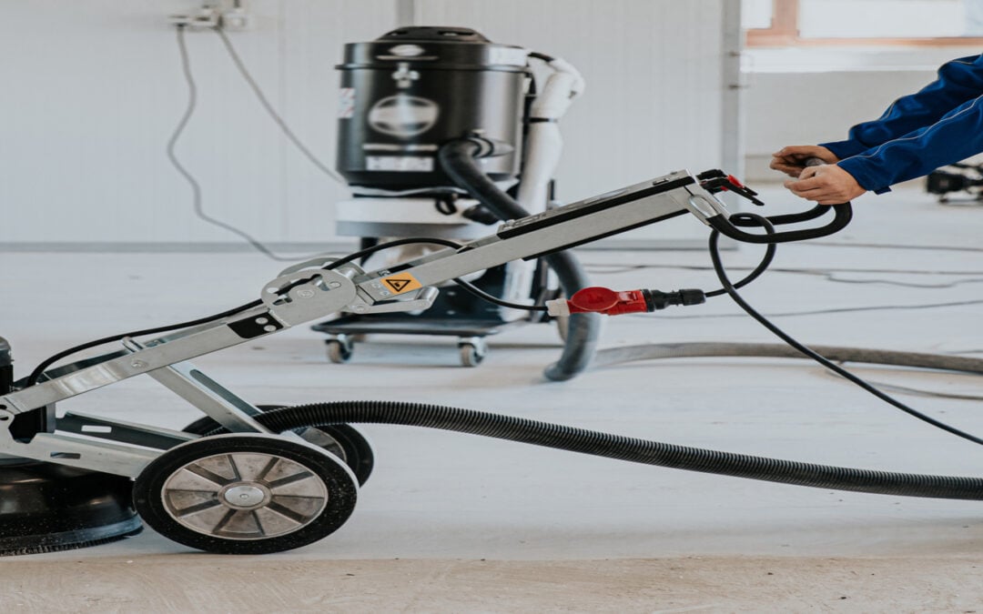 Construction worker using machine polishing surface floor smoothing and finishing hardener on concrete surface.